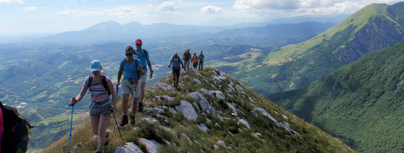 Wanderer auf einem Bergpfad mit weitem Ausblick in den Monti Sibillini